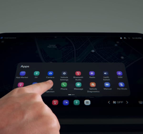 Ein Finger berührt den Touchscreen eines Infotainment-Systems, auf dem ein App-Menü in einem Fahrzeug angezeigt wird.